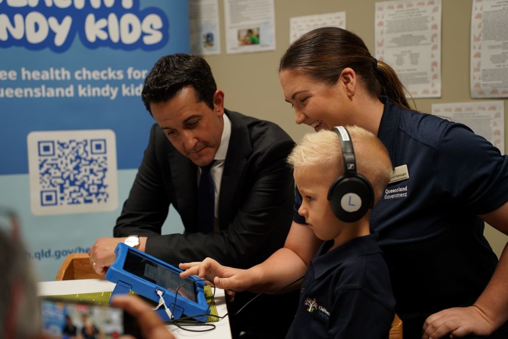 Premier and speech pathologist sit with kindy student receiving a free kindy health check.